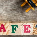 Toy plastic bulldozer hold toy block letter s to fulfill word safety with foklift on wood background