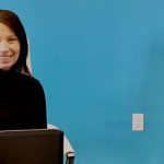 Woman smiling behind computer screen